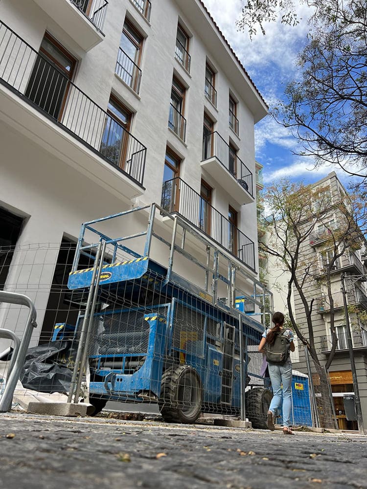 Una plataforma eléctrica articulada trabajando en la reparación de una fachada urbana, ideal para alcanzar zonas de difícil acceso