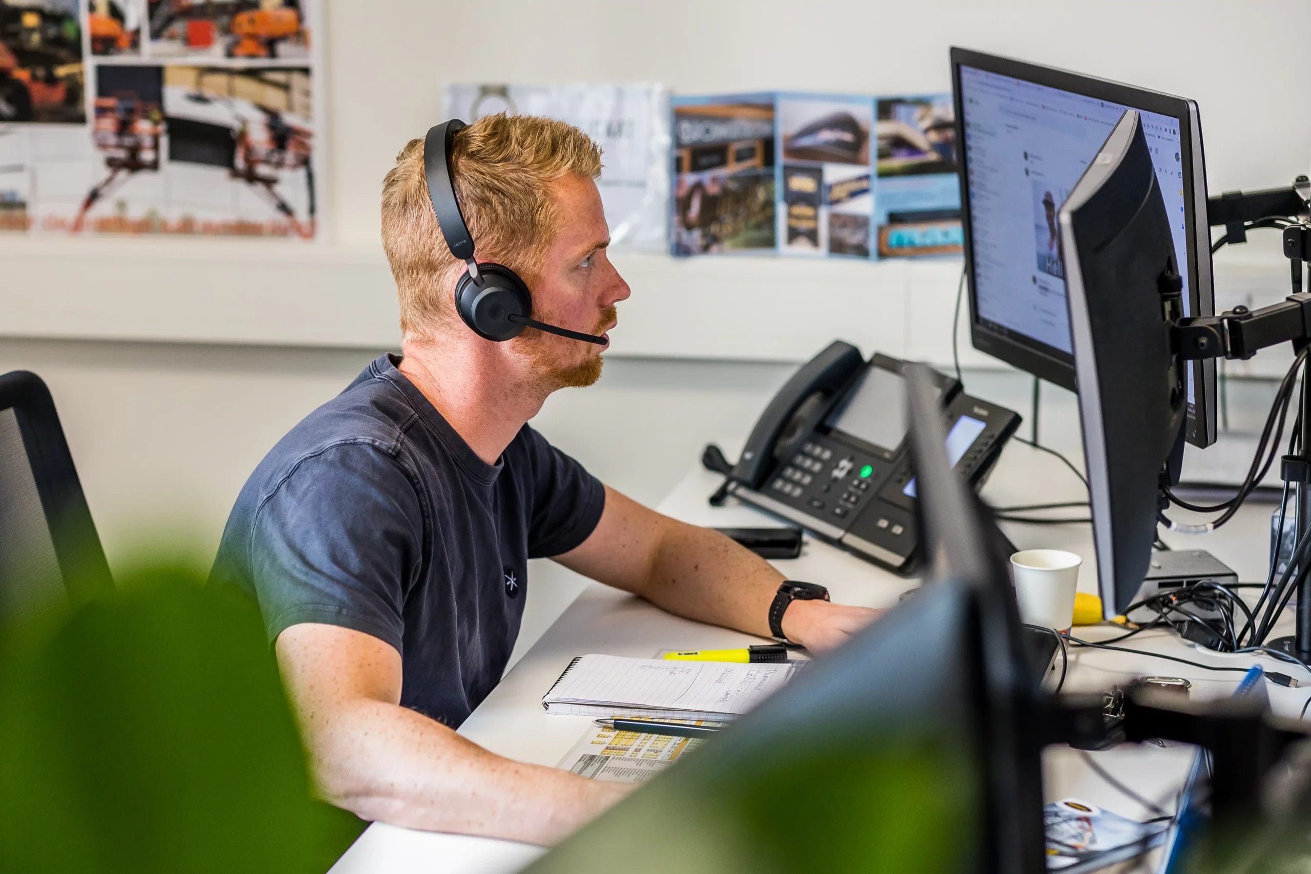 Man werkt achter een computer met een headset op 